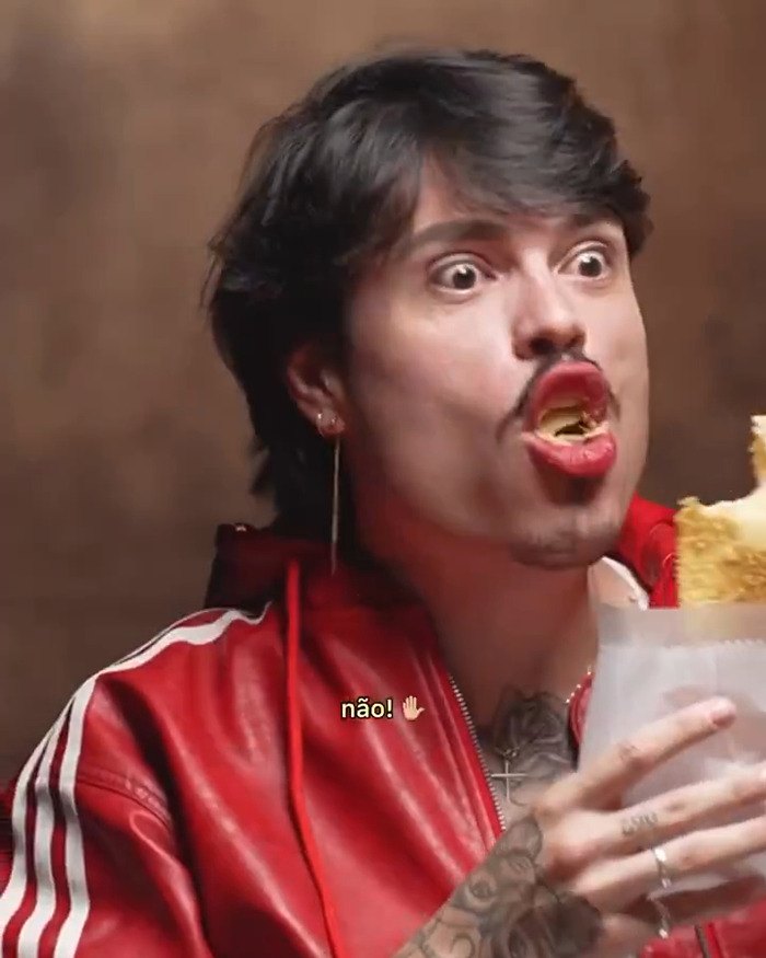 Individual in a red jacket appearing surprised while eating, connected to reactions involving Millie Bobby Brown and Brazilians. Individual in a red jacket appearing surprised while eating, connected to reactions involving Millie Bobby Brown and Brazilians.
