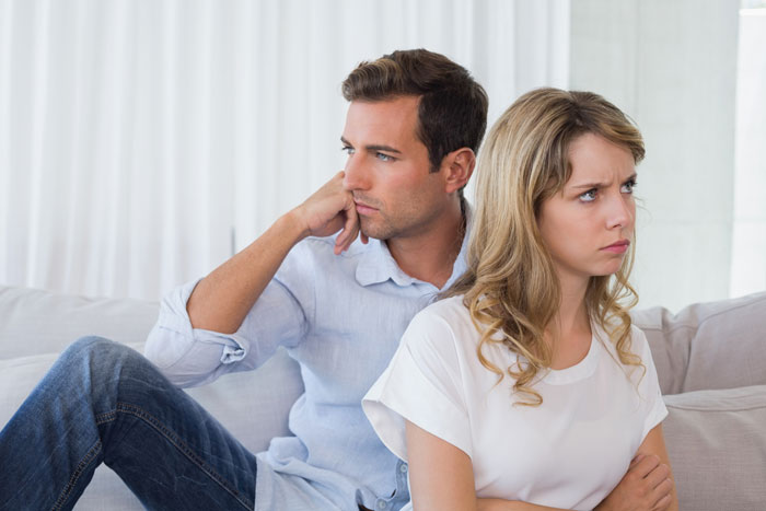 Couple having serious discussion about motherhood on a couch, showing emotional tension and differing perspectives. Couple having serious discussion about motherhood on a couch, showing emotional tension and differing perspectives.