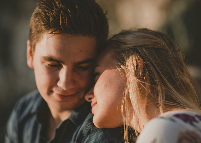 Couple sitting together, woman leans on boyfriend looking relaxed, highlighting his normal appearance despite sleeping habits. Couple sitting together, woman leans on boyfriend looking relaxed, highlighting his normal appearance despite sleeping habits.