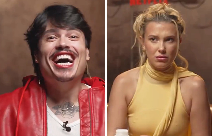 Person in a red jacket laughing, while another in a yellow top looks displeased, amid controversial interviews. Person in a red jacket laughing, while another in a yellow top looks displeased, amid controversial interviews.