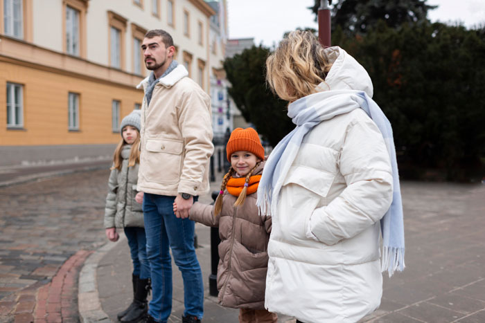 A man stands with his wife and three kids outdoors, all dressed warmly for winter. A man stands with his wife and three kids outdoors, all dressed warmly for winter.
