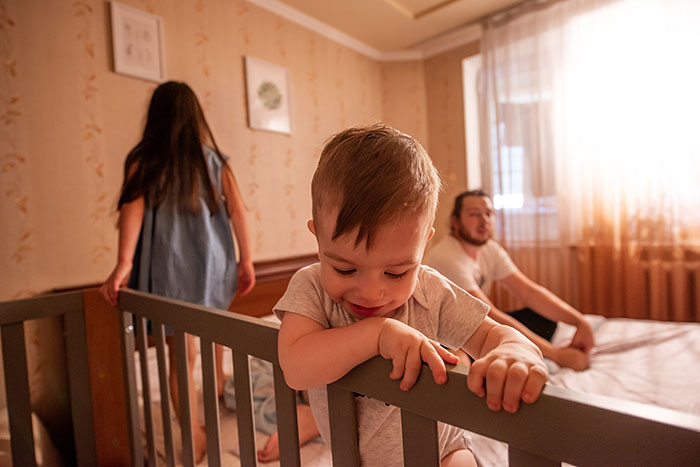 Man with children in a bedroom, highlighting family dynamics and parenting challenges. Man with children in a bedroom, highlighting family dynamics and parenting challenges.