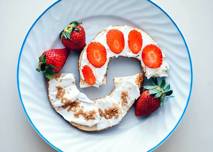 Bagel with cream cheese and strawberries on a plate, highlighting ridiculous things people got bullied for.