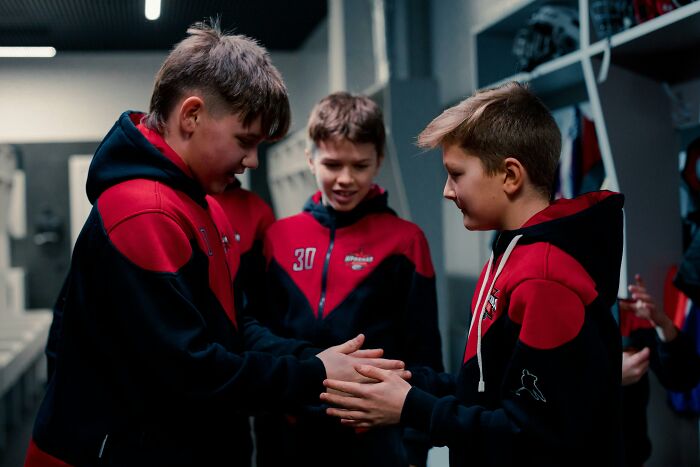 Three boys in red and black jackets interacting, capturing the theme of bullying over ridiculous things.