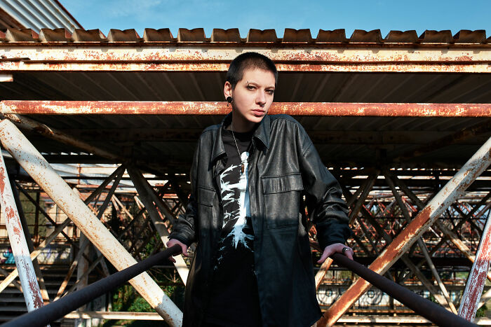 Person posing outdoors in a black leather jacket, highlighting individuality despite past bullying.
