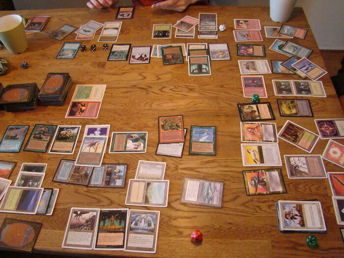 A table filled with trading cards and dice, showing a game in progress.