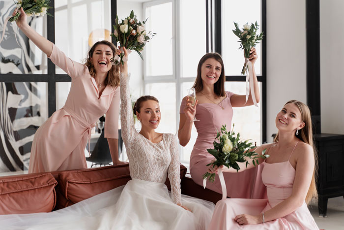 Bridesmaids in pink dresses and bride smiling and holding bouquets indoors, with natural light. Bridesmaids in pink dresses and bride smiling and holding bouquets indoors, with natural light.