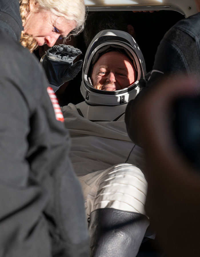 Astronaut in space suit smiling inside capsule, highlighting effects of 9-month space mission. Astronaut in space suit smiling inside capsule, highlighting effects of 9-month space mission.