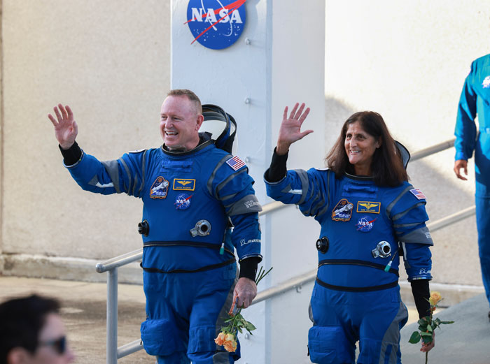 Astronauts in blue suits waving, highlighting effects of space travel on the body. Astronauts in blue suits waving, highlighting effects of space travel on the body.