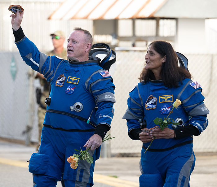 NASA astronaut waves with colleague after Earth return, holding flowers. NASA astronaut waves with colleague after Earth return, holding flowers.