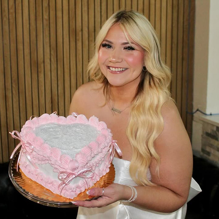 Young woman holding a heart-shaped cake at her bachelorette party, smiling brightly. Young woman holding a heart-shaped cake at her bachelorette party, smiling brightly.