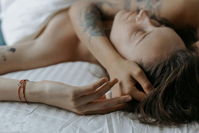 Person resting on bed with tattoos visible, representing a scene related to uncovering a cheating affair. Person resting on bed with tattoos visible, representing a scene related to uncovering a cheating affair.