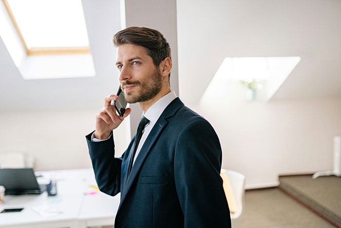 Man in a suit on the phone, appearing contemplative in a bright office setting. Man in a suit on the phone, appearing contemplative in a bright office setting.