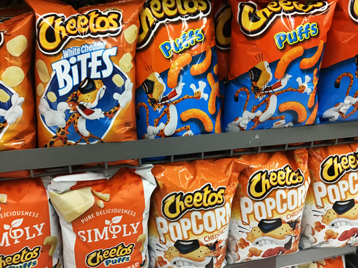 Cheetos snack bags on a shelf, highlighting different flavors like Puffs and Popcorn. Cheetos snack bags on a shelf, highlighting different flavors like Puffs and Popcorn.