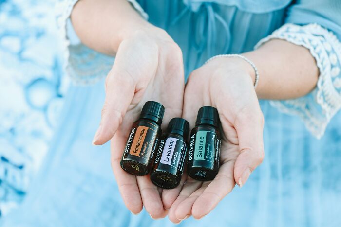 Hands holding essential oils, often misunderstood as healthy, set against a blue background.