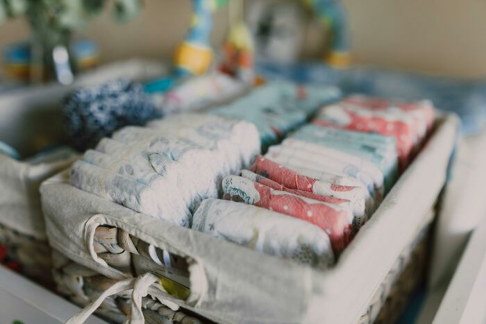 Basket of colorful baby diapers on a changing table, related to childfree friend group dynamics. Basket of colorful baby diapers on a changing table, related to childfree friend group dynamics.