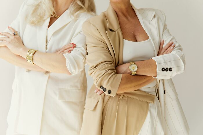 Two women in stylish suits standing with arms crossed, highlighting childfree friendships and related drama. Two women in stylish suits standing with arms crossed, highlighting childfree friendships and related drama.