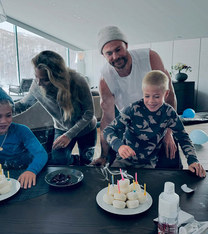 Family gathering with Chris Hemsworth, children at table with birthday candles, sparking controversy. Family gathering with Chris Hemsworth, children at table with birthday candles, sparking controversy.