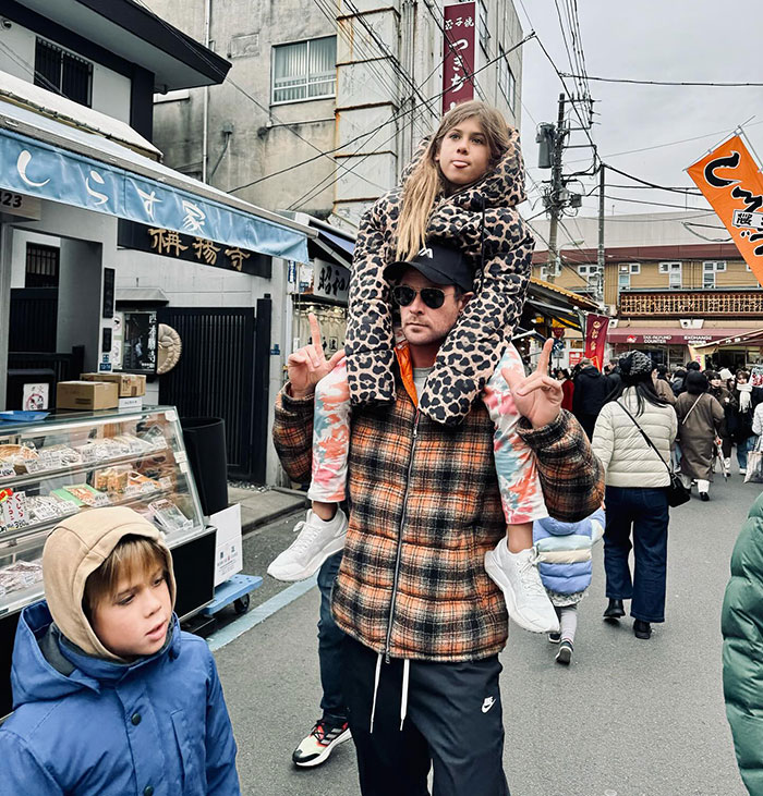 Man in plaid jacket with child on shoulders, standing on street. Man in plaid jacket with child on shoulders, standing on street.