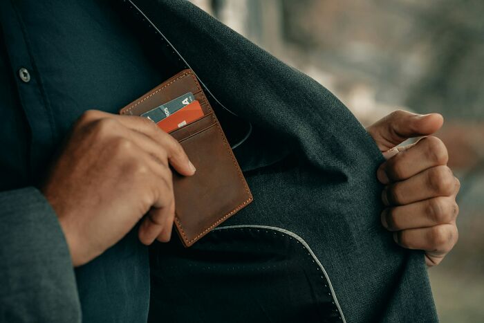 A person putting a card wallet into a jacket pocket, challenging stereotypes.