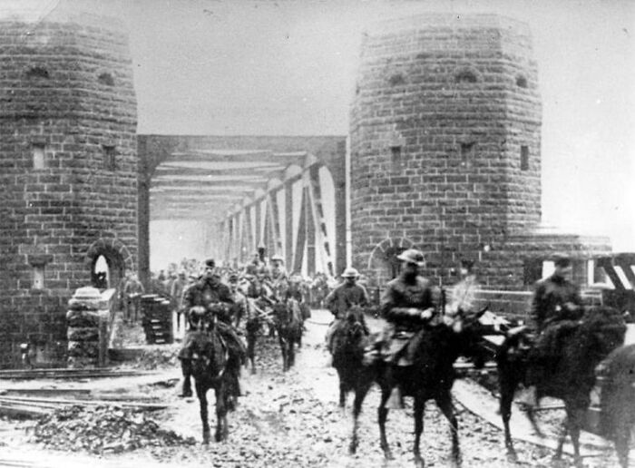 Riders on horseback crossing a historic stone bridge, related to Napoleon returning from exile.