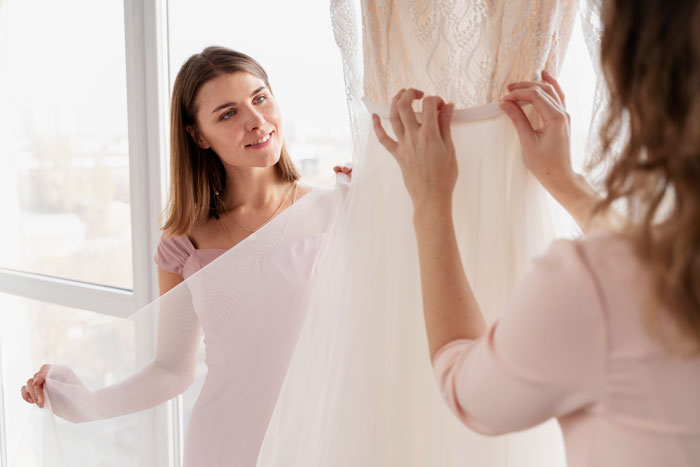 Friend assists with wedding dress fitting, showcasing wedding prep labor. Friend assists with wedding dress fitting, showcasing wedding prep labor.
