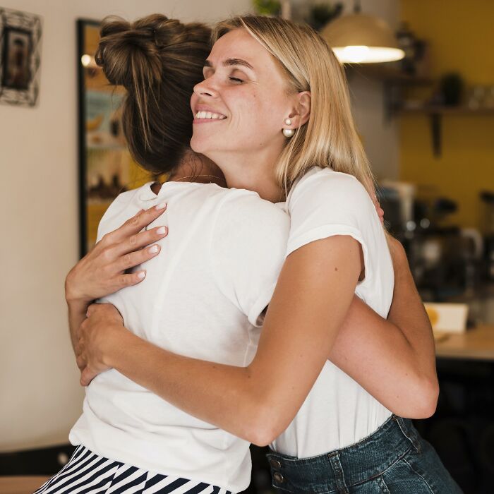 Two women hugging warmly in a cozy room, capturing a moment of joy and connection.