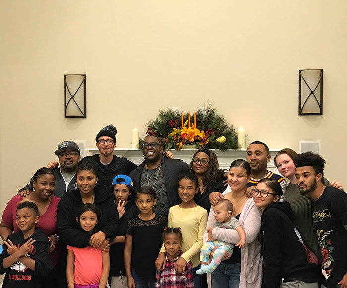 A large family gathered in front of a decorated mantel, smiling together for a group photo. A large family gathered in front of a decorated mantel, smiling together for a group photo.