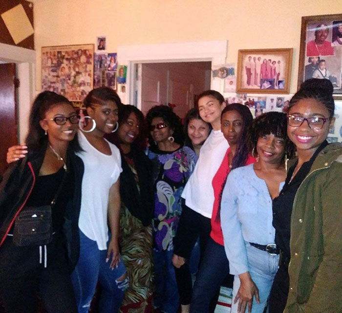 Group of women smiling indoors, in a room filled with family photos. Group of women smiling indoors, in a room filled with family photos.