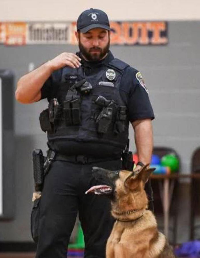 Police officer with service dog in uniform, inside a gym. Police officer with service dog in uniform, inside a gym.