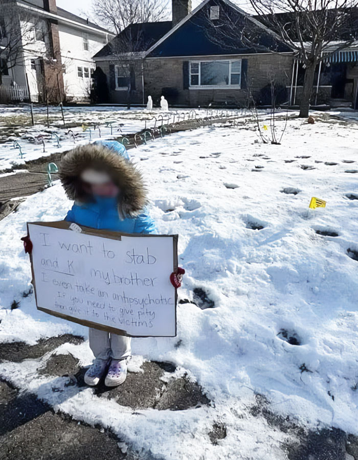 Young child in winter coat stands in snow holding a sign as a police officer's punishment. Young child in winter coat stands in snow holding a sign as a police officer's punishment.