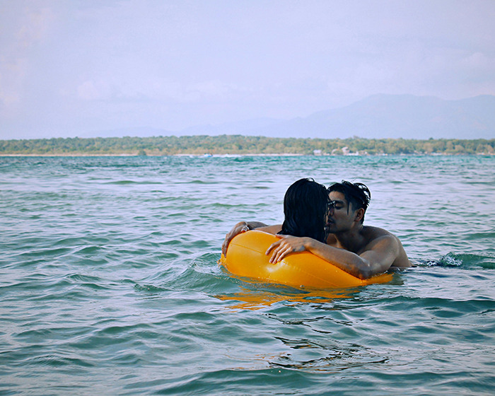Couple embracing in the water at family swimming spot with orange inflatable. Couple embracing in the water at family swimming spot with orange inflatable.