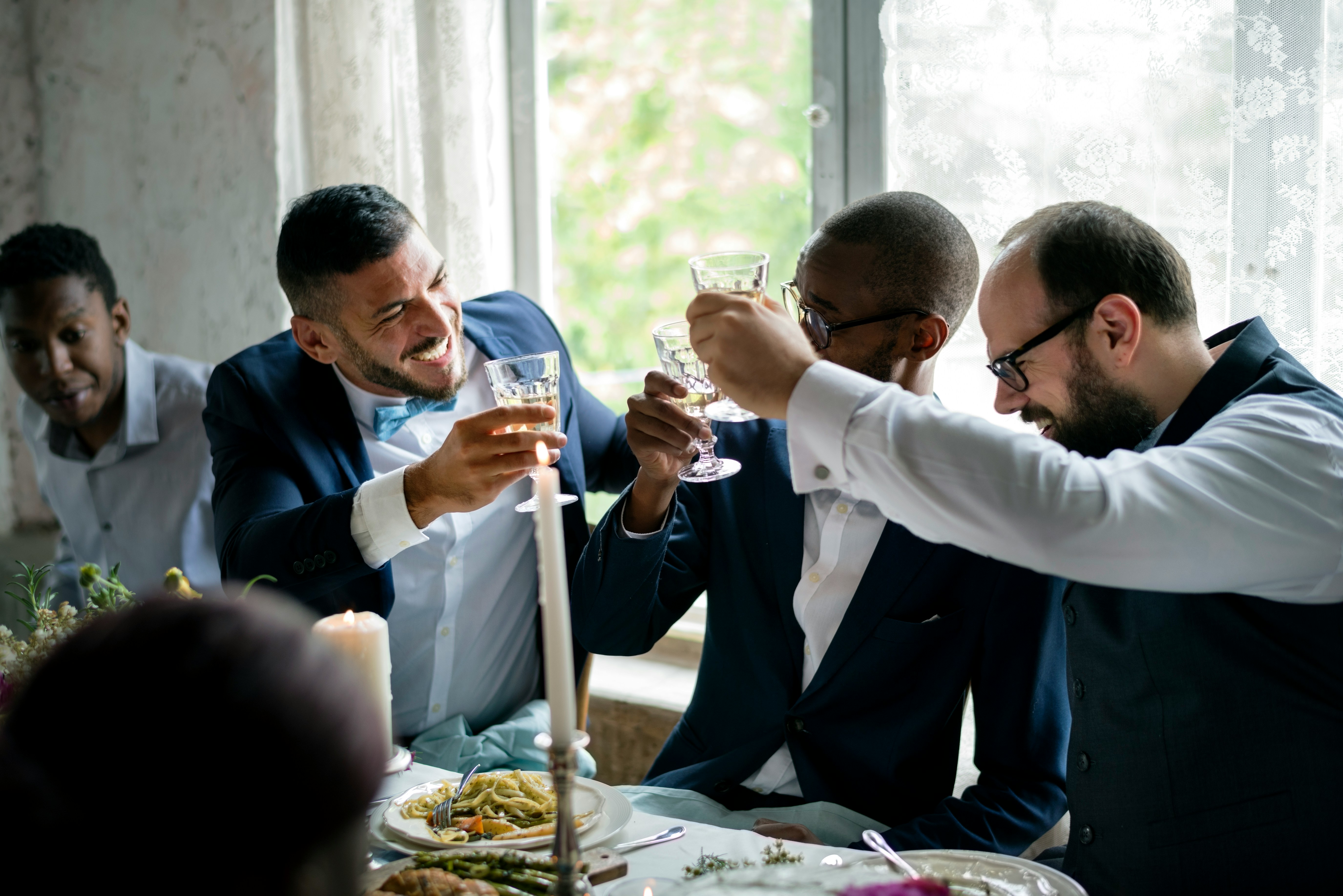Men in suits celebrating with drinks during a birthday dinner. Men in suits celebrating with drinks during a birthday dinner.