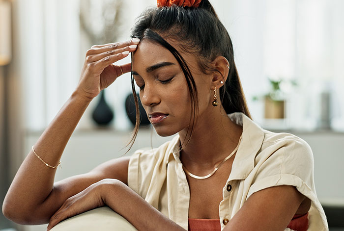 Woman looking stressed, considering care for stepsiblings if needed, sitting indoors in a thoughtful pose. Woman looking stressed, considering care for stepsiblings if needed, sitting indoors in a thoughtful pose.