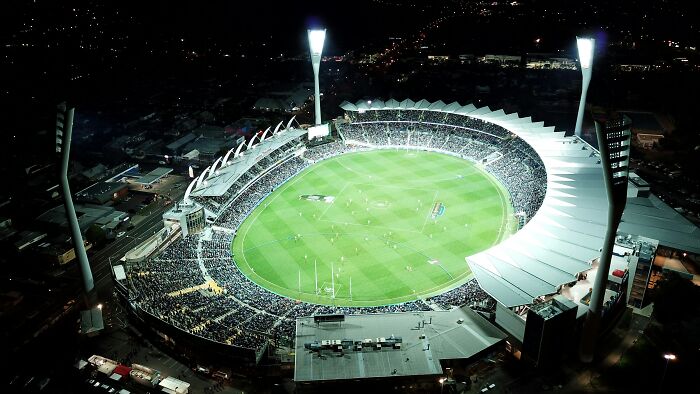 Aerial night view of a brightly lit soccer stadium filled with fans, showcasing one of the iconic cathedrals of soccer.