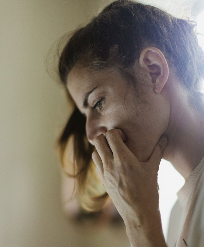Person looking thoughtful, hand on mouth, contemplating sterilization decision amid partner disagreement. Person looking thoughtful, hand on mouth, contemplating sterilization decision amid partner disagreement.