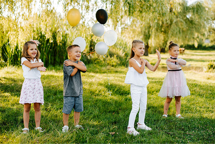 Children playing at a birthday party outdoors, with colorful balloons in the background. Children playing at a birthday party outdoors, with colorful balloons in the background.