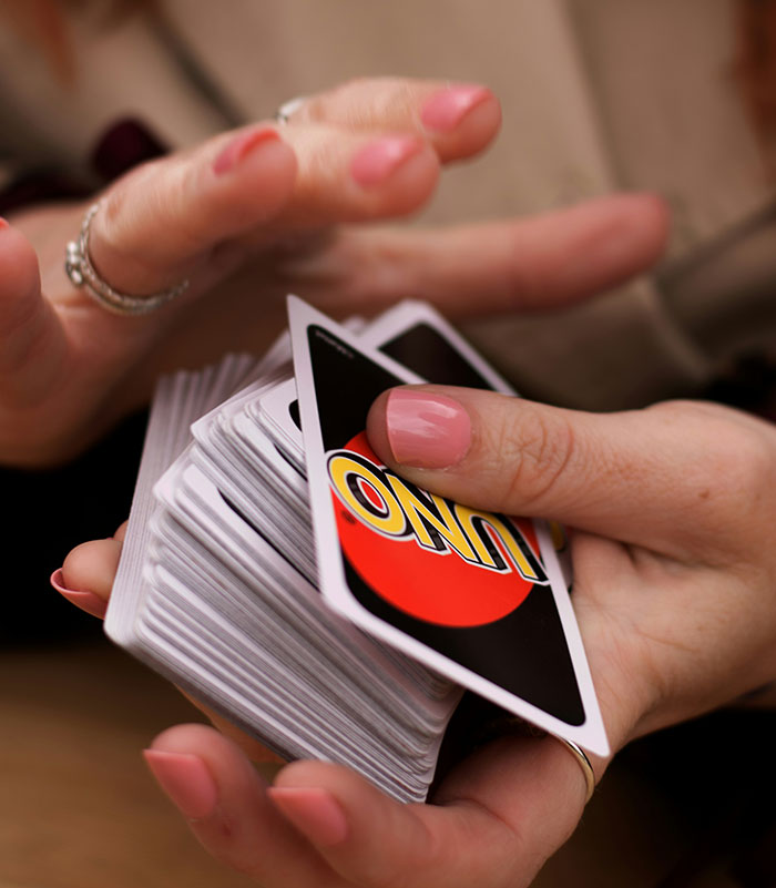 Hands holding a deck of Uno cards, capturing a fun and strategic brand moment.