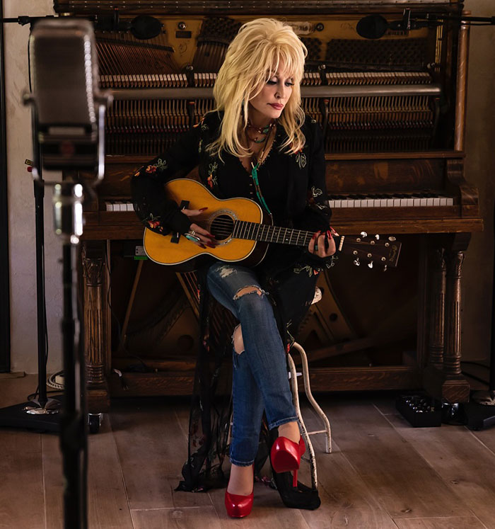 Singer with guitar near a piano, releasing a heartfelt song dedicated to her late husband. Singer with guitar near a piano, releasing a heartfelt song dedicated to her late husband.