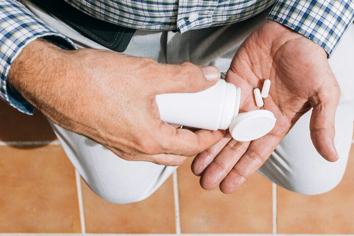 A person holding a pill bottle over their hand, highlighting job misconceptions in healthcare professions.