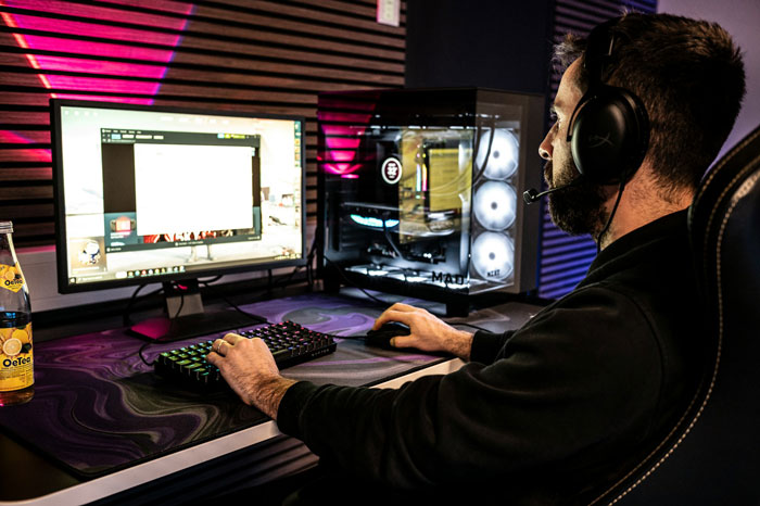 Man wearing headset using computer, dimly lit gaming setup, gaslighting theme. Man wearing headset using computer, dimly lit gaming setup, gaslighting theme.