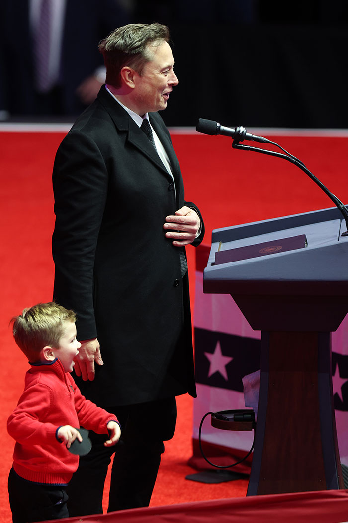 Man in black coat and child in red sweater at podium, related to controversy involving children’s privacy. Man in black coat and child in red sweater at podium, related to controversy involving children’s privacy.