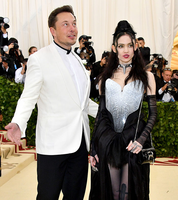 Elon Musk and Grimes pose at a public event, surrounded by photographers, amid privacy debate. Elon Musk and Grimes pose at a public event, surrounded by photographers, amid privacy debate.