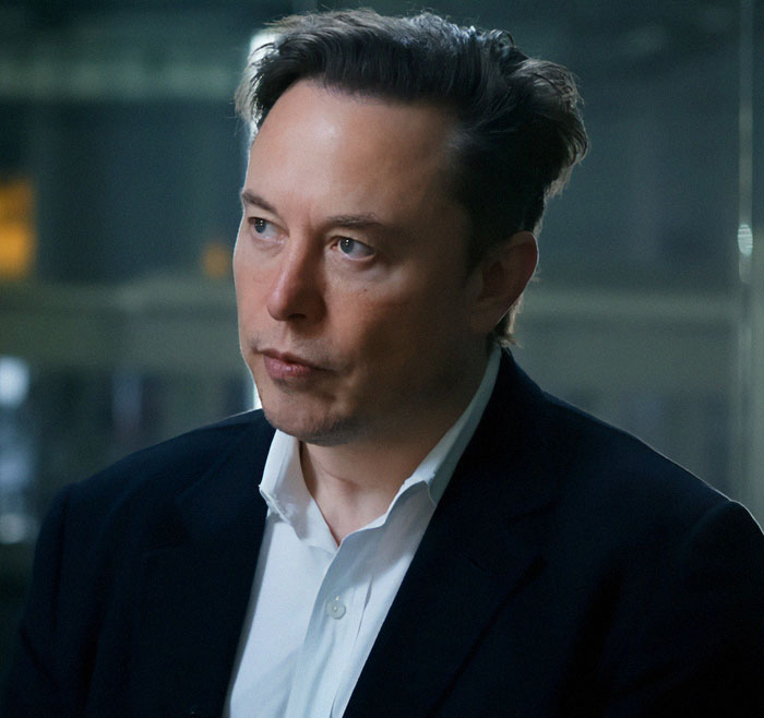 A man with short hair, in a suit, looking thoughtful in an indoor setting. A man with short hair, in a suit, looking thoughtful in an indoor setting.