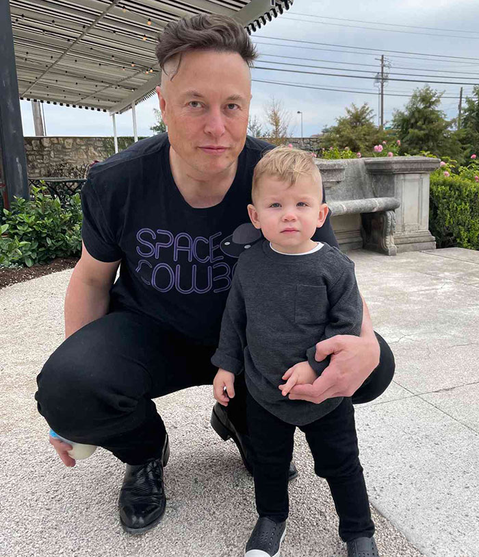 Man in a "Space Cowboy" shirt kneeling beside a toddler outdoors. Man in a "Space Cowboy" shirt kneeling beside a toddler outdoors.