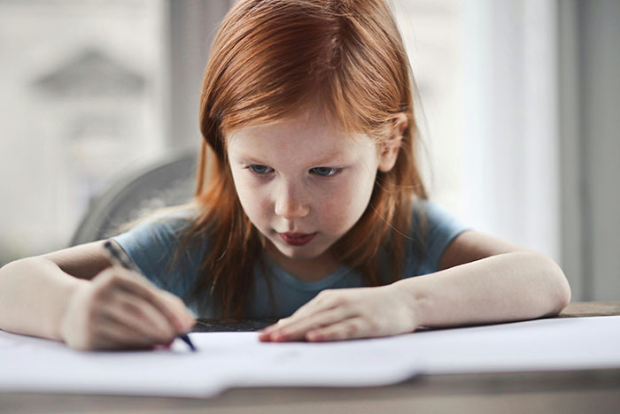 Young girl with red hair, focused on drawing with a pencil, linked to university funds and past behavior story. Young girl with red hair, focused on drawing with a pencil, linked to university funds and past behavior story.