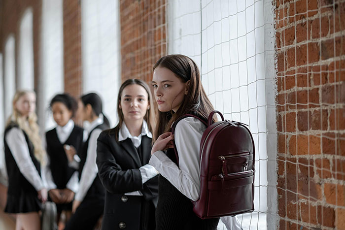 Teen with red backpack looking upset at school hallway due to university fund issues stemming from past behavior. Teen with red backpack looking upset at school hallway due to university fund issues stemming from past behavior.