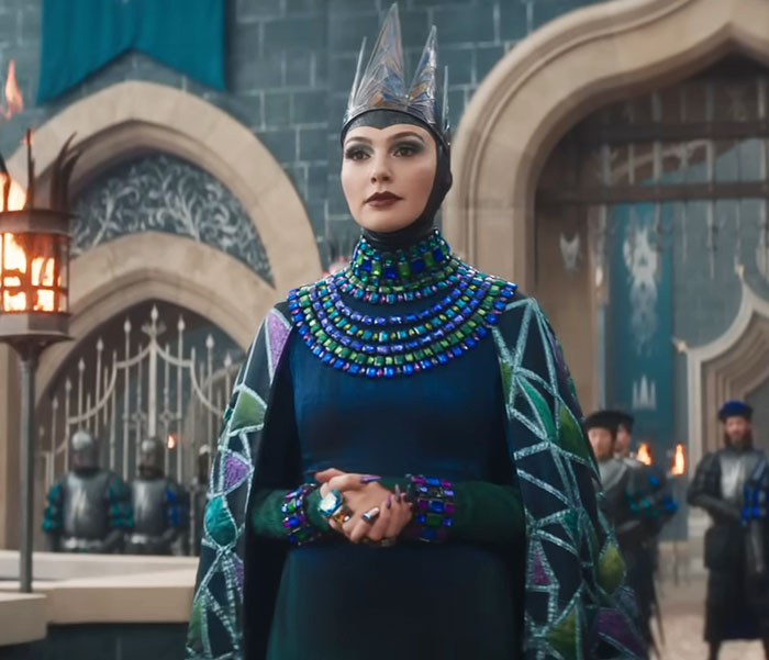 Actress in regal attire from 'Snow White' film scene, set in a castle with guards in the background. Actress in regal attire from 'Snow White' film scene, set in a castle with guards in the background.