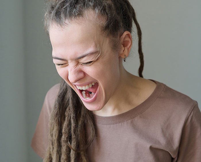 Pregnant woman with dreadlocks, wearing a brown shirt, laughing loudly. Pregnant woman with dreadlocks, wearing a brown shirt, laughing loudly.