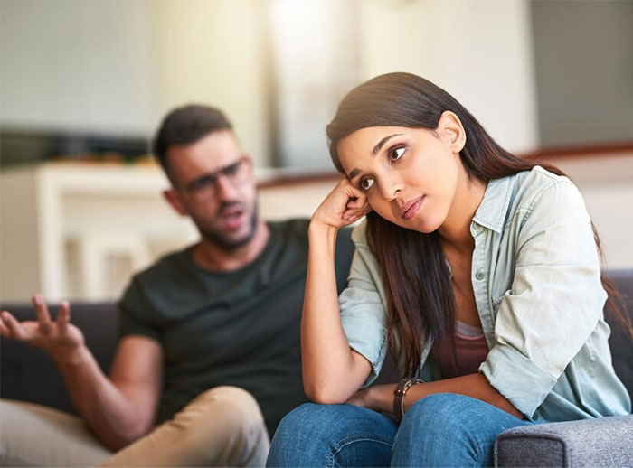 Couple arguing about Hispanic cooking, man gesturing and woman looking away, both seated in a living room. Couple arguing about Hispanic cooking, man gesturing and woman looking away, both seated in a living room.